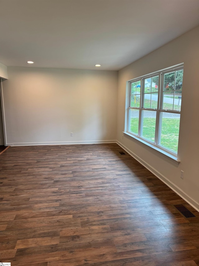 empty room featuring dark wood finished floors, baseboards, visible vents, and recessed lighting
