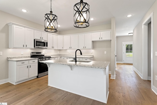 kitchen featuring a sink, stainless steel appliances, an island with sink, and white cabinets