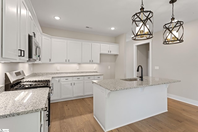 kitchen featuring light wood finished floors, white cabinetry, stainless steel appliances, and a sink