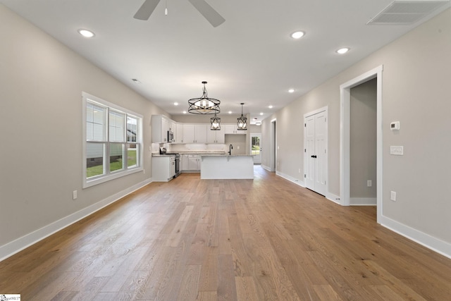 unfurnished living room with light wood-style flooring, a wealth of natural light, visible vents, and recessed lighting