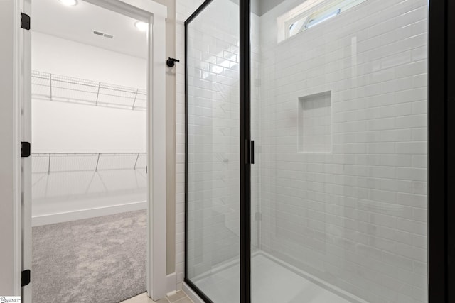 bathroom with a stall shower, a walk in closet, and visible vents
