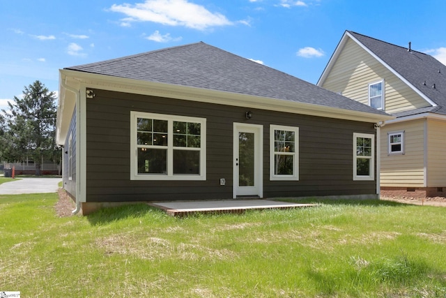 back of house featuring a shingled roof and a lawn