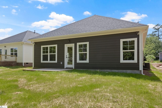 rear view of property featuring a patio area, a shingled roof, and a lawn