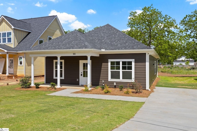craftsman house with a shingled roof, a porch, and a front yard