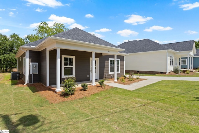 view of front of home with cooling unit, a shingled roof, covered porch, and a front lawn