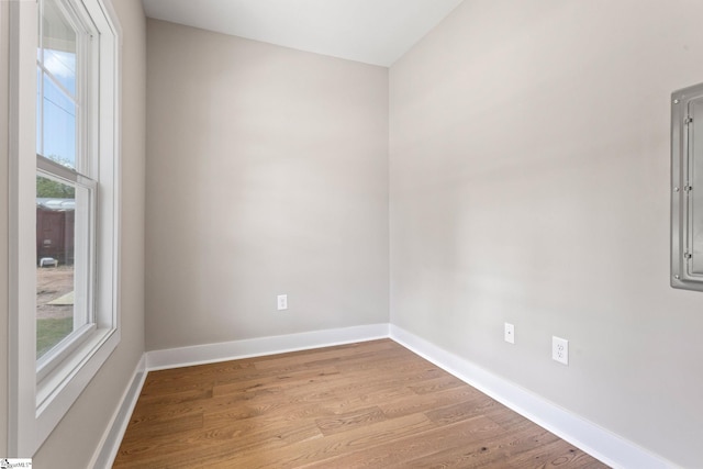 unfurnished room featuring baseboards, plenty of natural light, and wood finished floors