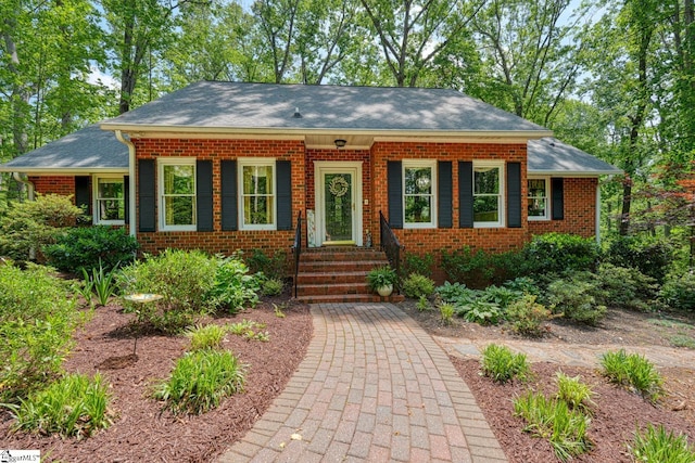 view of front of house featuring a shingled roof and brick siding