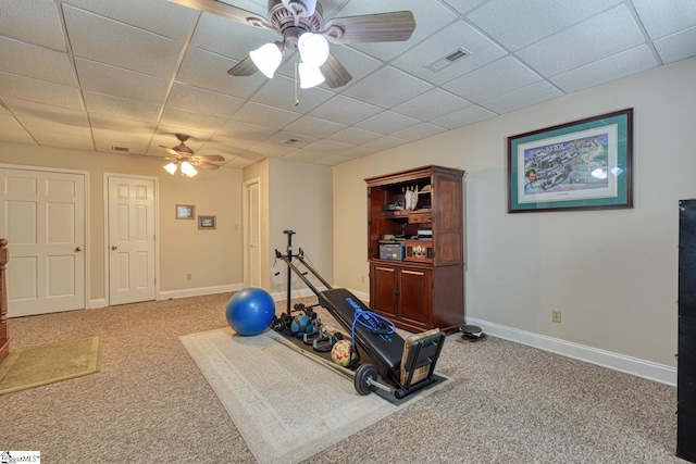 workout area featuring carpet, visible vents, a ceiling fan, and a paneled ceiling