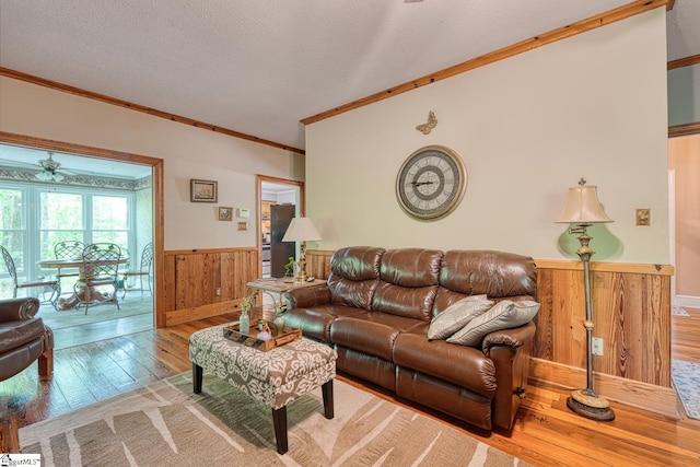 living room featuring wainscoting, ceiling fan, ornamental molding, and wooden walls