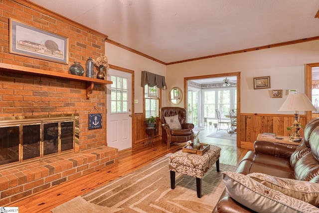 living area featuring a fireplace, crown molding, hardwood / wood-style floors, and a wainscoted wall