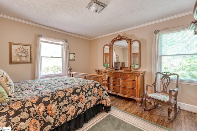 bedroom with baseboards, crown molding, a textured ceiling, and wood finished floors