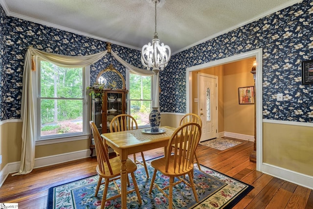 dining area with a chandelier, ornamental molding, a textured ceiling, and wallpapered walls