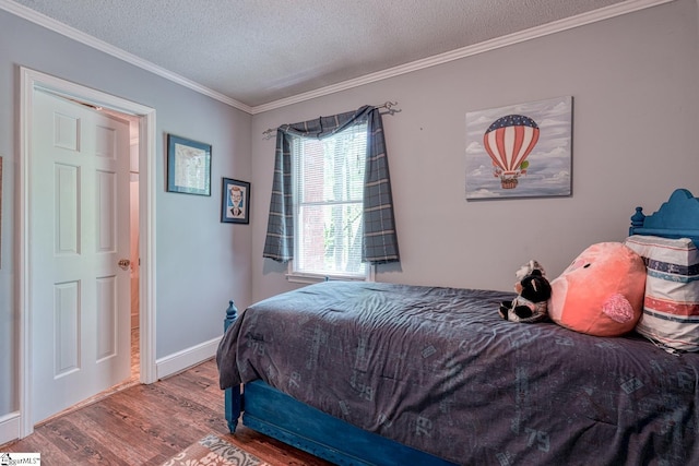 bedroom with baseboards, ornamental molding, a textured ceiling, and wood finished floors