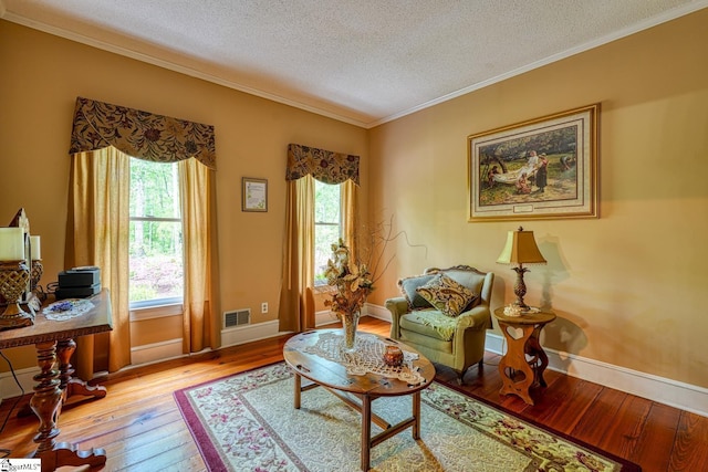 living area featuring a healthy amount of sunlight, a textured ceiling, hardwood / wood-style floors, and visible vents