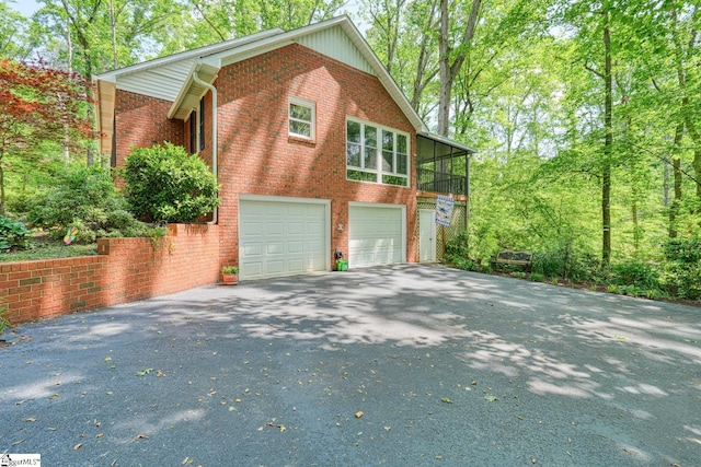 view of home's exterior featuring an attached garage, brick siding, and driveway