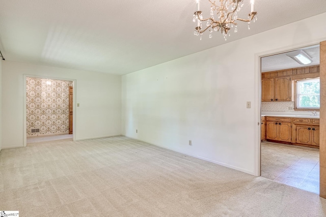 unfurnished living room with a chandelier, baseboards, a sink, and light carpet