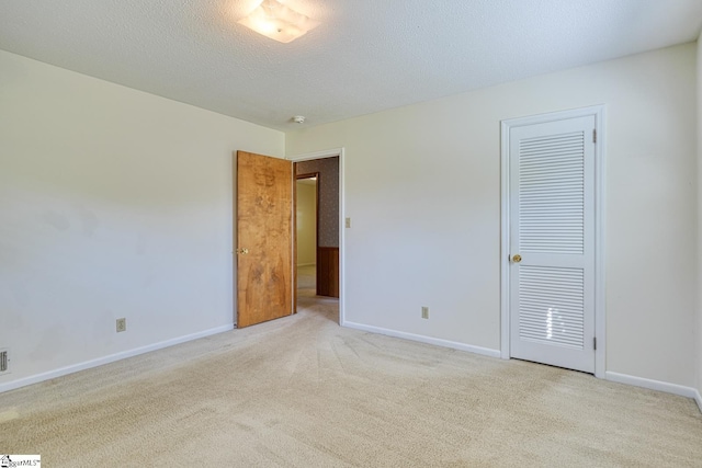 unfurnished bedroom with a textured ceiling, carpet flooring, and baseboards