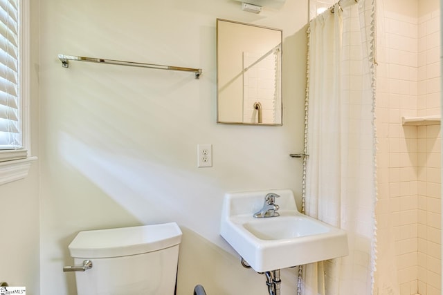full bath with toilet, a shower with curtain, and a sink