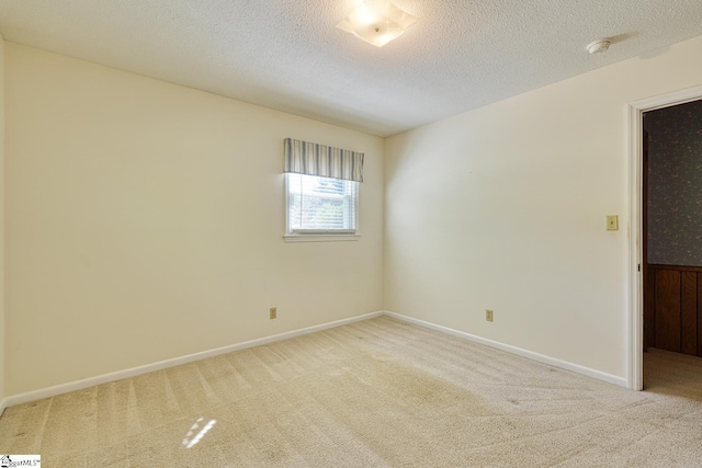 unfurnished room with a textured ceiling, carpet floors, and baseboards