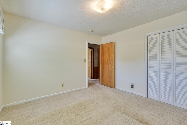 unfurnished bedroom featuring a closet, light carpet, and baseboards