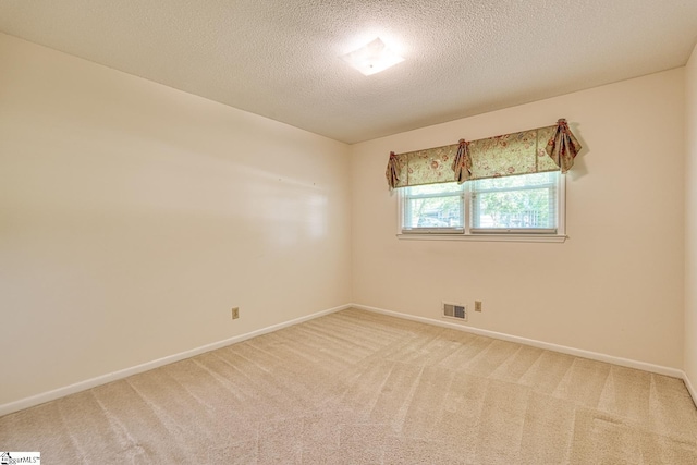 unfurnished room featuring light colored carpet, a textured ceiling, visible vents, and baseboards