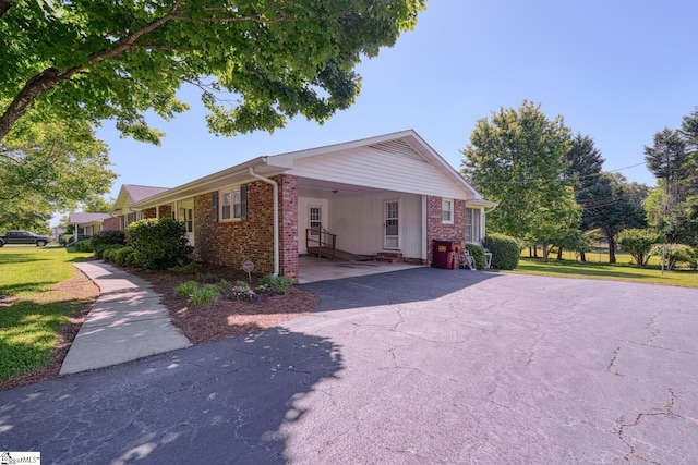 view of front facade featuring a front yard, an attached carport, brick siding, and aphalt driveway