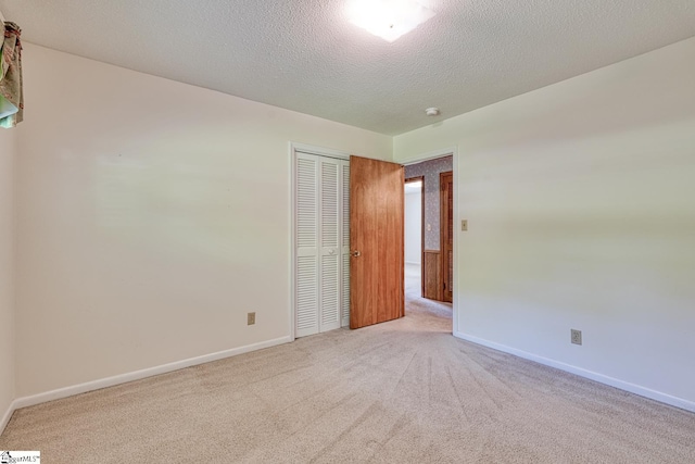 spare room featuring a textured ceiling, baseboards, and carpet