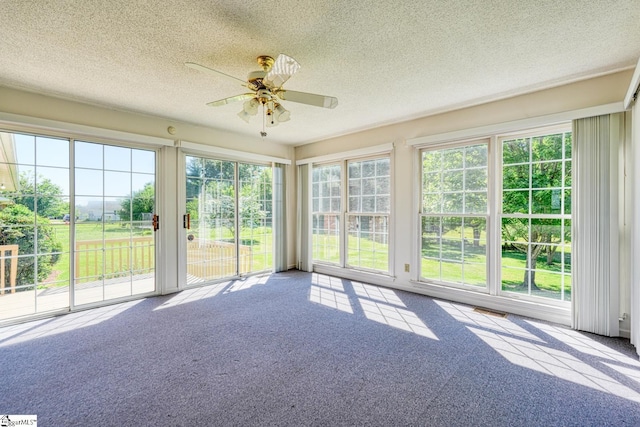 unfurnished sunroom with a textured ceiling, carpet, plenty of natural light, and visible vents