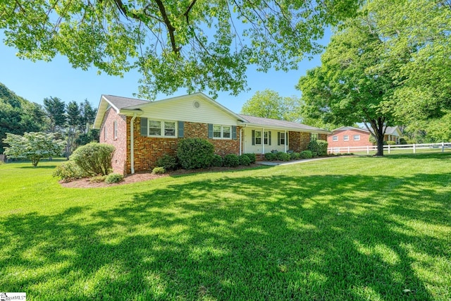 ranch-style home featuring a front lawn, brick siding, and fence