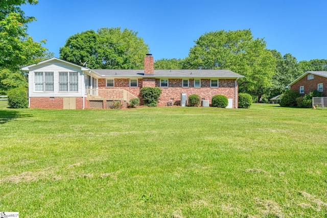 rear view of house with brick siding, a chimney, and a lawn