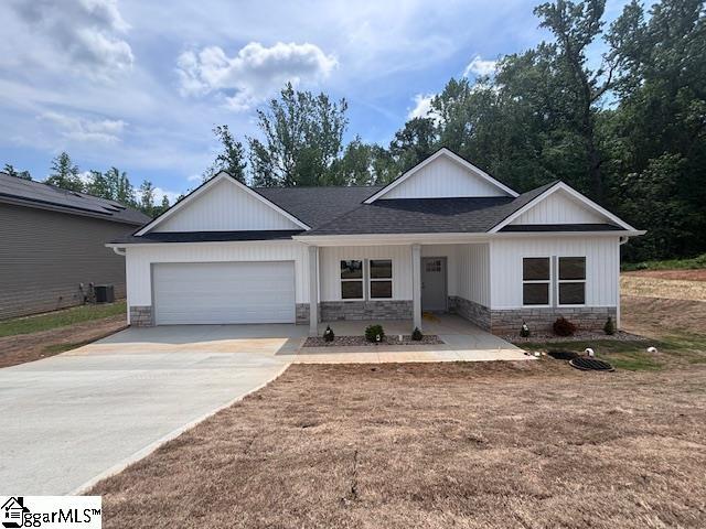 single story home featuring roof with shingles, concrete driveway, an attached garage, and stone siding