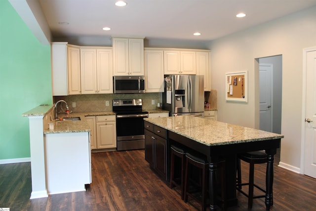 kitchen with dark wood-style floors, backsplash, light stone counters, and appliances with stainless steel finishes