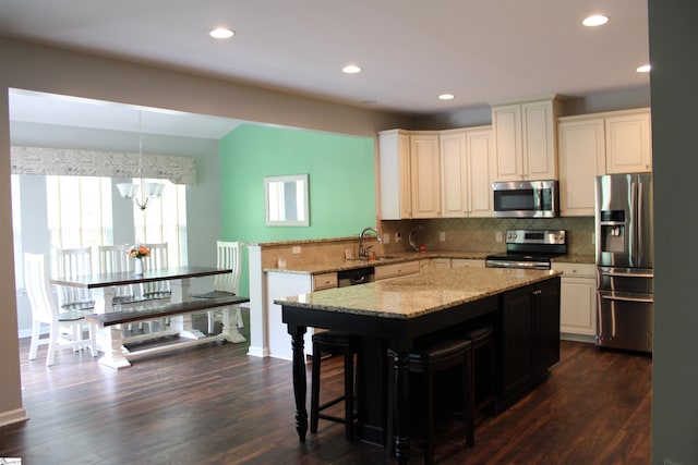 kitchen featuring backsplash, a notable chandelier, appliances with stainless steel finishes, and a sink