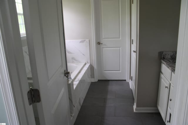 bathroom with vanity, a garden tub, baseboards, and tile patterned floors