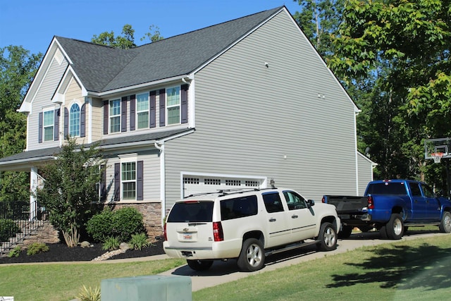 view of side of property with an attached garage, a shingled roof, and a yard