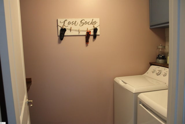 washroom featuring washing machine and clothes dryer and cabinet space