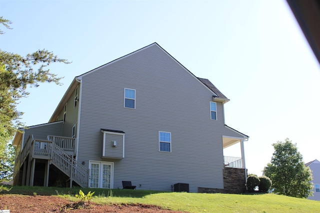 view of side of property featuring central AC unit, a yard, and stairway