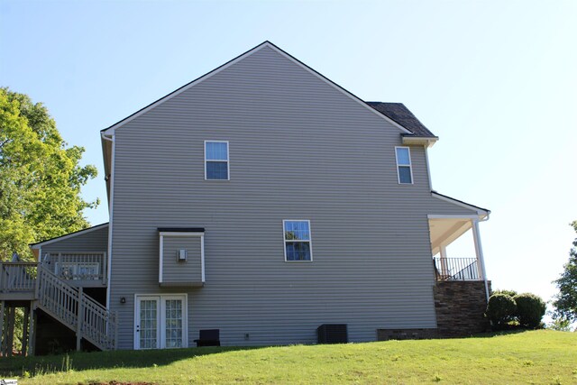 view of side of property with central air condition unit, stairs, a wooden deck, and a lawn