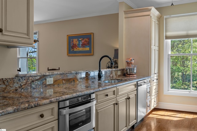 kitchen featuring stainless steel appliances, plenty of natural light, a sink, crown molding, and wood finished floors