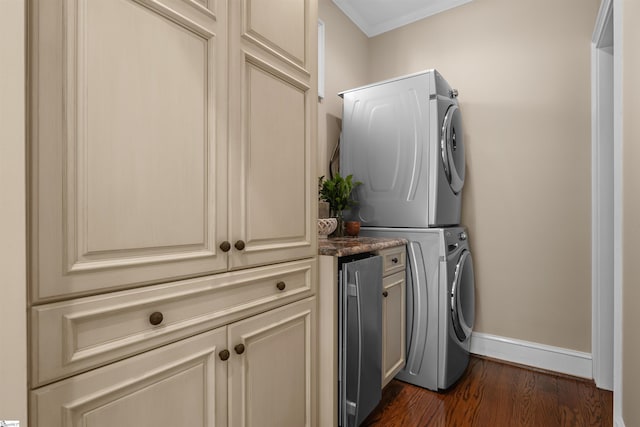 laundry area with estacked washer and dryer, cabinet space, dark wood-style flooring, baseboards, and ornamental molding