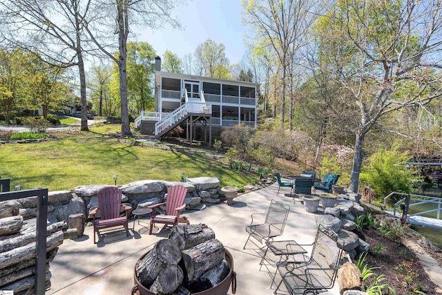 view of patio / terrace featuring a sunroom, stairs, and an outdoor fire pit