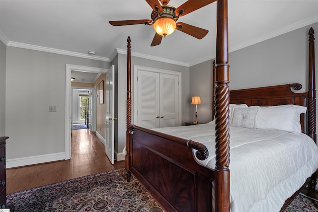 bedroom featuring wood finished floors, baseboards, a closet, crown molding, and a ceiling fan