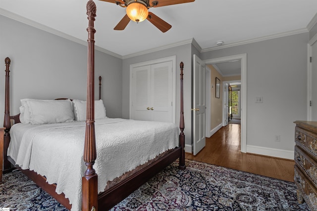 bedroom with wood finished floors, a closet, crown molding, baseboards, and a ceiling fan