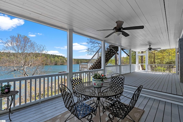 wooden deck with stairs, a water view, ceiling fan, and outdoor dining space
