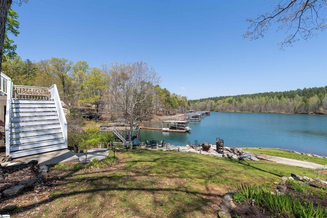 water view featuring stairway, a heavily wooded area, and a dock
