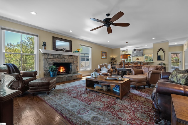 living room featuring a ceiling fan, wood finished floors, plenty of natural light, ornamental molding, and recessed lighting