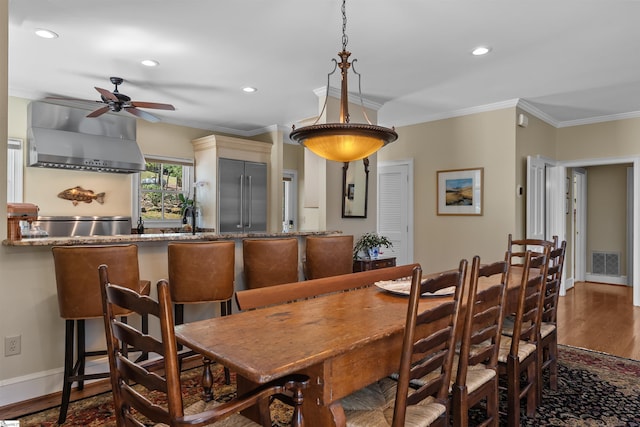 dining room with wood finished floors, ceiling fan, crown molding, recessed lighting, and baseboards