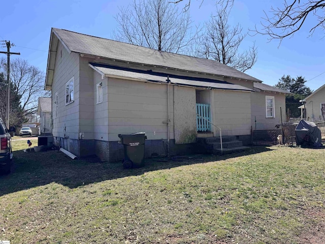 back of property featuring a lawn, crawl space, and roof with shingles