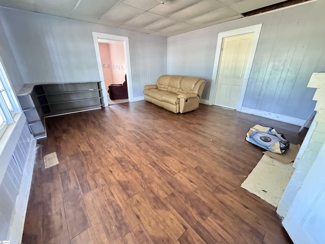 living area with dark wood-type flooring and a drop ceiling