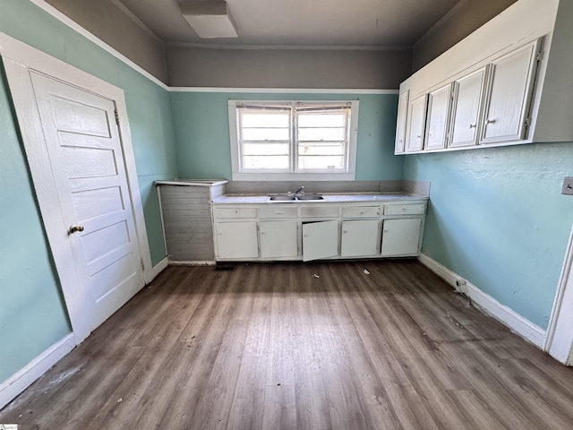laundry room featuring dark wood-style floors, baseboards, a sink, and crown molding